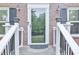 Close-up of a home's front entrance featuring glass storm door and white railings and brick facade at 5083 Lambeth Nw Ct, Acworth, GA 30101