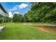 Sprawling backyard with a fire pit, swing, mature trees, and wooden fence at 7307 Banks Mill Rd, Douglasville, GA 30135