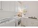 Bright laundry room with white cabinetry, modern appliances, and a sink, offering a functional space at 1128 Bellewood Sq, Dunwoody, GA 30338