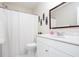 White bathroom with sink, toilet, shower with white curtain, and decorative mirror at 1533 Fallen Leaf Sw Dr, Marietta, GA 30064