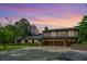 Stunning brick home featuring a three-car garage and lush landscaping against a colorful sunset backdrop at 204 Mt Moriah Rd, Auburn, GA 30011