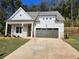 Charming one-story home featuring a light gray facade, a two-car garage and a covered porch at 3032 Farm Tract Trl, Woodstock, GA 30189
