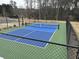 Outdoor pickleball court enclosed with fencing, surrounded by a natural landscape at 3032 Farm Tract Trl, Woodstock, GA 30189