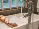 Close up of soaking tub with bubbles, a faucet, and a window with blinds at 3167 Blairhill Ct, Atlanta, GA 30340