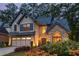 Charming two-story home at dusk with stone accents, gray shutters, a two-car garage, and lit landscaping at 3167 Blairhill Ct, Atlanta, GA 30340