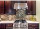 Close-up of kitchen features a stainless steel stove, dark wood cabinets, and mosaic backsplash at 3167 Blairhill Ct, Atlanta, GA 30340