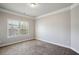A well-lit bedroom featuring plush carpeting, crown molding, and a window with natural light and backyard views at 3345 Palmer Lake Pointe, Douglasville, GA 30135