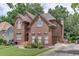 Side view of a two-story brick home featuring manicured lawn and garden beds, enhancing its picturesque setting at 380 Chandler Ct, Sugar Hill, GA 30518