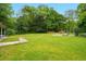 Lush backyard featuring a large, open lawn with mature trees and foliage at 426 College E St, Bowdon, GA 30108