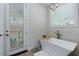 Bright bathroom featuring a standalone tub with modern fixtures, neutral tiles and a balcony door at 451 Burton Dr # 32, Alpharetta, GA 30009