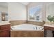 Bathroom featuring a large soaking tub under a window, a dual-sink vanity, and neutral color palette at 2710 Irwin Ct, Cumming, GA 30041