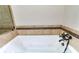 Close-up of bathtub with bronze faucet and wall with tan tile in bathroom at 349 Harris Loop, Dallas, GA 30157
