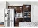 Modern kitchen with stainless steel appliances, dark wood cabinets, and granite countertops and a stainless steel refrigerator at 345 Varenna Ln, Sugar Hill, GA 30518