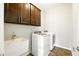 Well-lit laundry room with modern washer and dryer, sink, and storage cabinets at 345 Varenna Ln, Sugar Hill, GA 30518