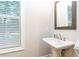 Bathroom with pedestal sink, mirror, and window offering natural light at 555 Letchas Ln, Alpharetta, GA 30009