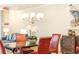 Elegant dining area featuring a glass table, red chairs, chandelier and crane artwork at 555 Letchas Ln, Alpharetta, GA 30009