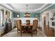 Elegant dining room with tray ceiling, wainscoting, stylish chandelier, and views of the fireplace and foyer at 5885 Wild Azalea Cv, Sugar Hill, GA 30518