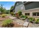 Exterior view of the home with stone pathway, lush landscaping, flowering shrubs, and verdant lawn at 5885 Wild Azalea Cv, Sugar Hill, GA 30518