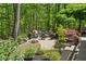 Secluded fire pit area surrounded by lush greenery, offering a tranquil and private space for relaxation at 5885 Wild Azalea Cv, Sugar Hill, GA 30518