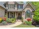 Inviting brick home with charming front porch, lush landscaping, and stone pathway, creating a warm and welcoming entrance at 5885 Wild Azalea Cv, Sugar Hill, GA 30518
