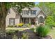 Charming brick home featuring a beautifully landscaped front yard with mature trees and colorful flower beds at 5885 Wild Azalea Cv, Sugar Hill, GA 30518