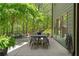 Outdoor dining area on the patio, showcasing a table with chairs, and a glimpse of the wooded backyard at 5885 Wild Azalea Cv, Sugar Hill, GA 30518