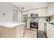Well-lit kitchen featuring stainless steel appliances and white cabinetry with a view into the living room at 11 Forrest Pl, Atlanta, GA 30328
