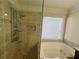 Elegant bathroom with a glass shower, jacuzzi tub, and a window letting in natural light at 1417 Wind Chime Ct, Lawrenceville, GA 30045