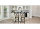 Home bar with white cabinets and bar stool seating, complete with a counter and mini fridge in a recreational space at 5625 Buckleigh Pointe, Suwanee, GA 30024