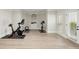 Bright home gym featuring exercise equipment, a mirror, and light colored flooring with a door to the exterior at 5625 Buckleigh Pointe, Suwanee, GA 30024