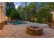 Inviting backyard featuring a stone fire pit, pool with waterfall, lush landscaping, and string lights for ambiance at 2480 Flint Creek Dr, Cumming, GA 30041