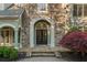 Inviting stone front entrance with double doors, a stone walkway, and lush landscaping, creating a warm and welcoming feel at 2480 Flint Creek Dr, Cumming, GA 30041