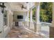 Covered outdoor kitchen and lounge area with stone floors, ceiling fan, TV, and white cabinets near a pool at 2480 Flint Creek Dr, Cumming, GA 30041