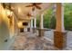 Covered outdoor kitchen and lounge area with stone floors, ceiling fan, TV, and white cabinets near a pool at 2480 Flint Creek Dr, Cumming, GA 30041