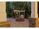 Outdoor stone kitchen with a grill and stone fire pit on a stone patio with string lights above at 2480 Flint Creek Dr, Cumming, GA 30041
