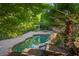 Backyard swimming pool with lush greenery and a stone patio, offering a private and serene outdoor experience at 2480 Flint Creek Dr, Cumming, GA 30041