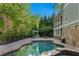 Beautiful backyard oasis with a kidney-shaped swimming pool, stone patio, outdoor kitchen, and mature trees at 2480 Flint Creek Dr, Cumming, GA 30041