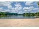 Sandy beach with clear lake waters, lush trees, and a clear blue sky in the background at 2981 Cardinal Lake Dr, Duluth, GA 30096
