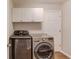 Laundry room with washer, dryer, cabinets, and a white door at 2981 Cardinal Lake Dr, Duluth, GA 30096
