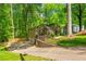 View of tan house with a two-car garage, driveway, and lush greenery surrounding the property at 3925 Rock Mill Pkwy, Marietta, GA 30062