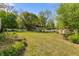 Large, verdant backyard featuring mature trees, established gardens, a gazebo, and pristine white fencing at 317 Ellenwood Dr, Bowdon, GA 30108