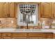 Well-lit kitchen features a farmhouse sink, checkered curtains, and brick backsplash at 317 Ellenwood Dr, Bowdon, GA 30108