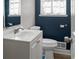 Stylish half bath with a sleek white vanity, a modern toilet, and charming navy blue accent wall at 3833 Coral Ln, Douglasville, GA 30135