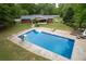 An aerial view of an in-ground pool with slide, ladders and sundeck, set in a spacious backyard with the home nearby at 3833 Coral Ln, Douglasville, GA 30135