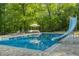 Inviting in-ground pool featuring a water slide and an umbrella-covered seating area for relaxing by the water at 3833 Coral Ln, Douglasville, GA 30135