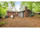 Backyard view of a charming home with a brick chimney and a screened-in porch overlooking the tree-filled yard at 3007 Stratford Arms Dr, Chamblee, GA 30341