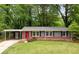 Charming single-story home with brick accents, a covered carport, a well-manicured lawn and a red front door at 3007 Stratford Arms Dr, Chamblee, GA 30341
