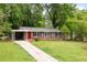 Charming single-story home with brick accents, a covered carport, a well-manicured lawn and a red front door at 3007 Stratford Arms Dr, Chamblee, GA 30341