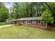 Charming single-story home with brick accents, a covered carport, a well-manicured lawn and a red front door at 3007 Stratford Arms Dr, Chamblee, GA 30341