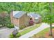 Aerial view of a brick home with a long driveway, mature landscaping and an attached garage at 3493 Wood Acres Blvd, Duluth, GA 30096